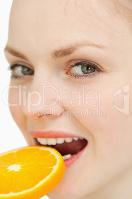Close up of a woman placing a slice of orange in her mouth