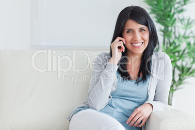 Woman talking on the phone while resting on a sofa