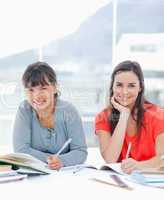 Two smiling women doing homework together