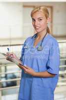 Blonde nurse writing on a clipboard