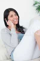 Woman smiling while sitting on a couch and phoning