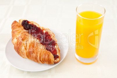 Croissant next to a glass of orange juice