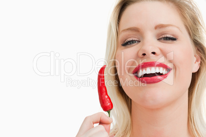 Blonde woman holding a chili while laughing