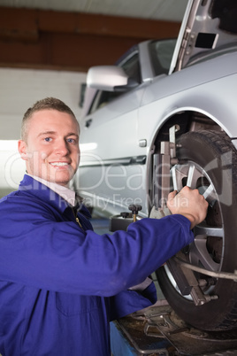 Smiling mechanic repairing a car wheel