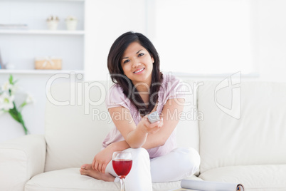 Woman sitting on a couch and holding a television remote