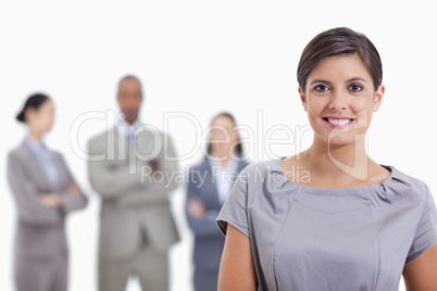 Close-up of a businesswoman smiling and a team in background