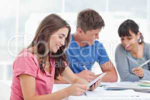 A girl looks at the tablet screen as she smiles with friends
