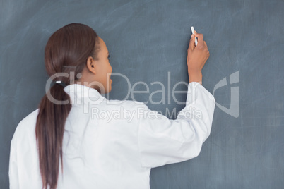 Teacher smiling while writing on a blackboard