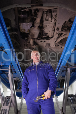 Mechanic standing up below a car