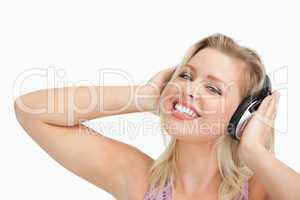 Blonde woman raising her arms while listening to music