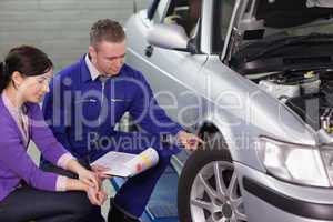 Mechanic touching the car wheel next to a client