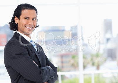 Executive standing upright in front of a window and looking towa