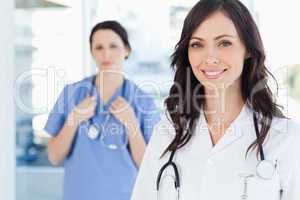 Smiling nurse accompanied by her colleague in the background