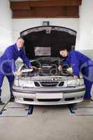 Mechanics smiling while leaning on a car