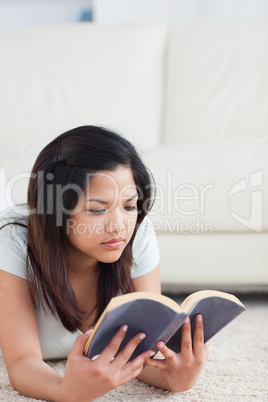Woman laying on the floor while reading a book