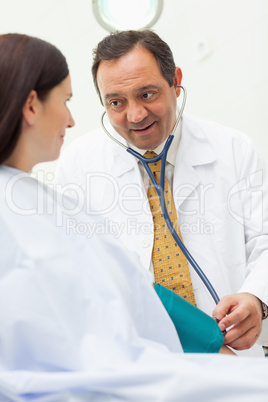 Doctor smiling while taking the blood pressure of a patient