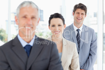 Young smiling executive following two business people