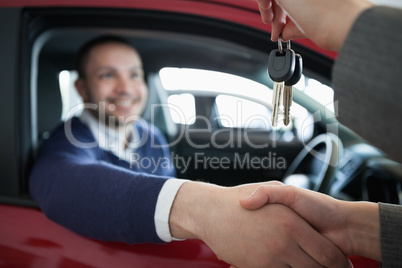Woman giving car keys while shaking hand