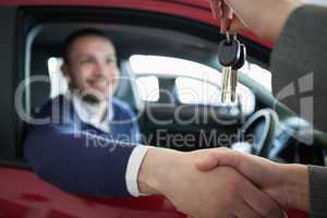 Woman giving car keys while shaking hand