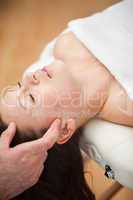 Woman lying on the back while being massaged on her head