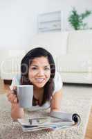 Woman holding a magazine as she lays on the floor