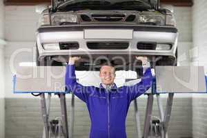 Smiling mechanic touching the below of a car