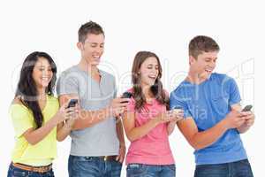 Four laughing friends sending texts on their phones