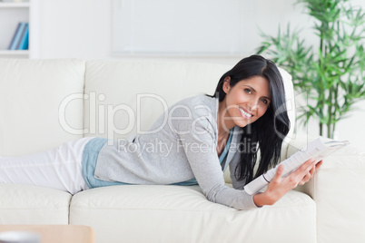 Woman holding a magazine while relaxing on a couch