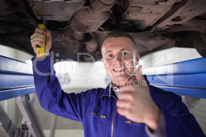 Smiling man repairing a car with his thumb up