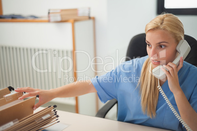 Nurse holding a phone while searching a folder