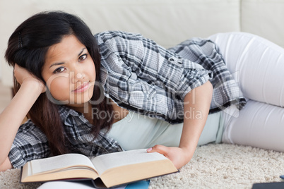 Woman lying on the floor while holding a book