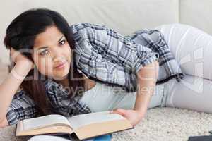 Woman lying on the floor while holding a book