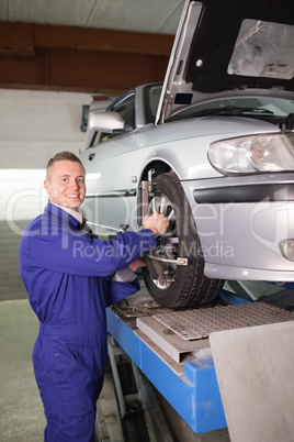 Mechanic standing while repairing a car wheel