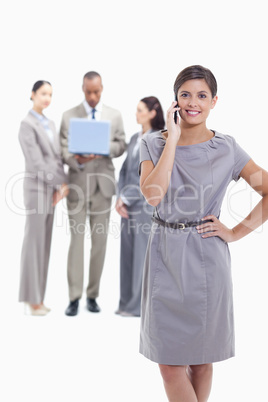 Businesswoman on the phone with a hand on her hip with co-worker