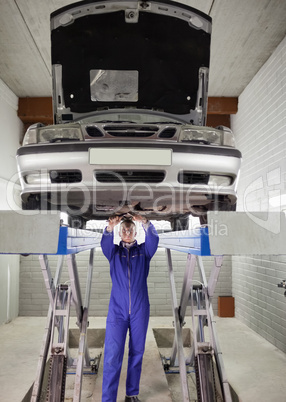 Mechanic standing while repairing a car