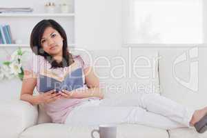 Woman lying on a couch while holding a book