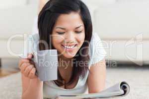 Smiling woman holding a cup and a magazine