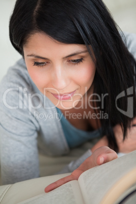 Woman reading a book as she lies on a couch