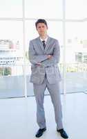 Businessman standing upright in front of a bright window and cro