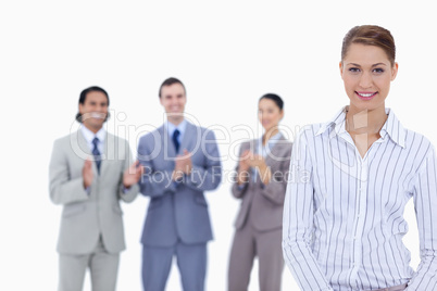 Close-up of a woman smiling with business people applauding