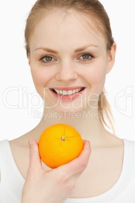 Close up of a woman presenting an orange while smiling