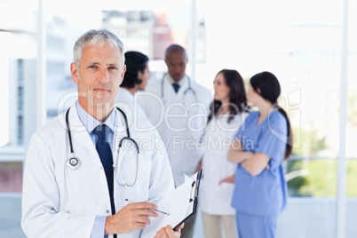 Mature doctor pointing at something on his clipboard