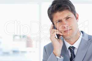 Young executive seriously talking on the phone in front of a win