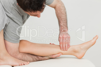 Serious osteopath massaging the shin bone of a patient