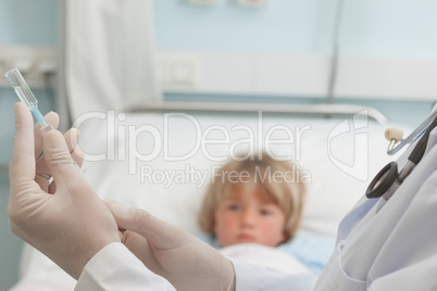 Doctor preparing a syringe in front of a child