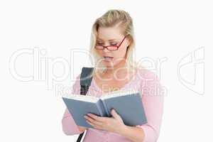 Serious woman reading a book while wearing glasses