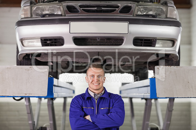 Mechanic with arms crossed below a car