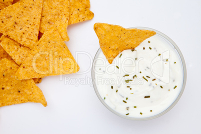Bowl of dip with herbs with a nacho dipped in it