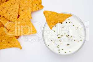 Bowl of dip with herbs with a nacho dipped in it