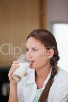 Woman drinking a glass of milk while looking away